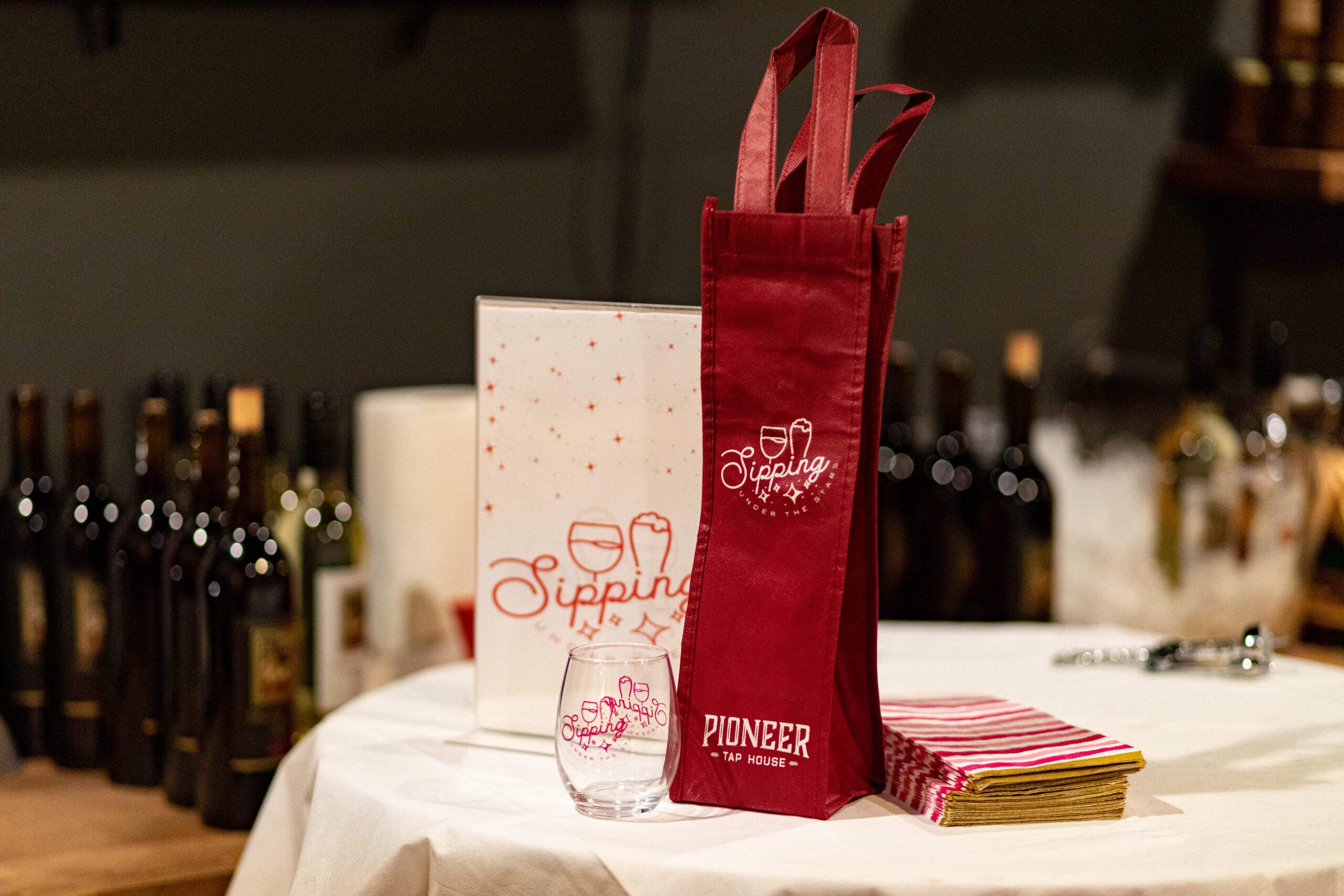 Sipping under the stars bag and wine glass featured with wine glasses presented in the background on a table